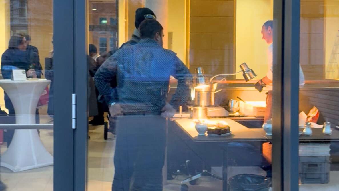 durch das Glasfenster sieht man Besucher:innen von sophie7 und den Koch mit Strudel